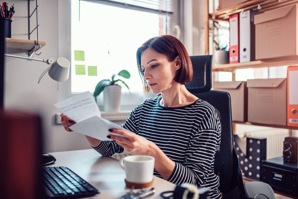 Worried woman sitting by the window reading mail in the office